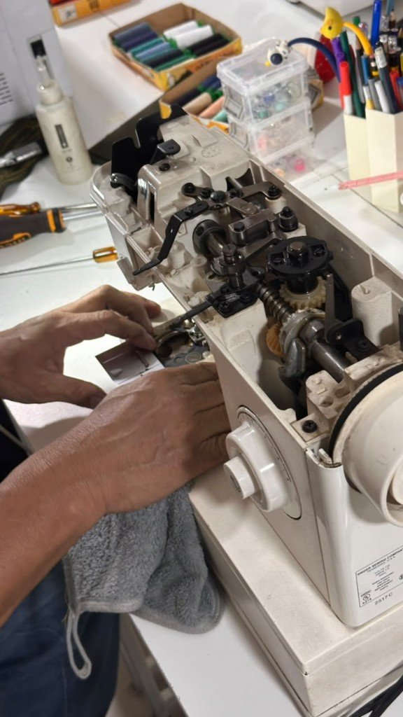 Técnico ajustando el mecanismo interno de una máquina de coser en GALO Atelier, El Salvador